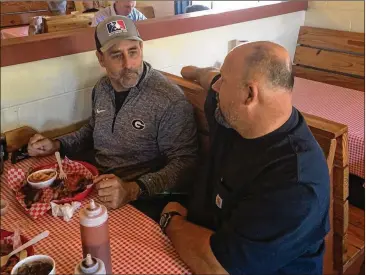  ?? PHOTOS BY STEVE HUMMER / SHUMMER@AJC.COM ?? Jake Fromm’s father Emerson (left) talks a little football and some hunting during a recent lunch break at Martin’s BBQ with restaurant owner Richard Martin.