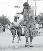  ?? Jon Shapley / Houston Chronicle ?? Eddie Abidde helps his daughter Addison, 4, ride her new bike down Live Oak Street during the Juneteenth celebratio­ns.