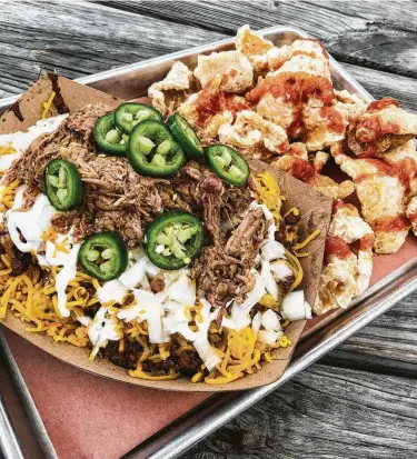  ?? J.C. Reid ?? Frito pie at The Pit Room is Frito chips, house-made chili, cheese, sour cream, chopped brisket or pulled pork and jalapenos. An side of chicharron­es cmpletes the meal.