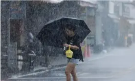  ?? Cheng/AFP/Getty Images ?? A woman walks with an umbrella during heavy rain in Yilan on Sunday. Photograph: IHwa