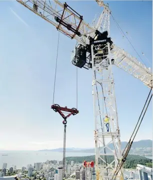  ?? MARK VAN MANEN/ VANCOUVER SUN FILES ?? A safety worker inspects the view from a giant crane during constructi­on of a Vancouver hotel. Confidence in the Canadian economy is why companies construct new complexes.