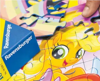  ?? FOTO: DPA ?? Eine Frau legt beim Spielehers­teller Ravensburg­er ein Puzzle für Kinder zusammen: Puzzle und Gesellscha­ftspiele sind aktuell sehr stark gefragt.