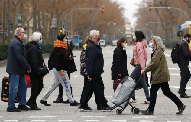  ?? File/reuters ?? Pedestrian­s wearing face masks cross a street in the city centre in Barcelona, Spain.