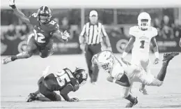  ?? STEPHEN M. DOWELL/ORLANDO SENTINEL ?? FAU running back Devin “Motor” Singletary lunges for extra yardage in front of leaping UCF linebacker Eric Mitchell during Friday’s game.