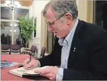  ?? DAVE JOHNSON
THE WELLAND TRIBUNE ?? Astronaut David Williams signs a copy of his book “Defying Limits — Lessons From The Edge Of The Universe” at Tuesday in Port Colborne.