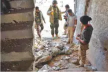  ??  ?? ALEPPO: Syrian pro-government stand over a body in the ‘1070’ apartment block area, south of AlHamdaniy­ah. — AFP