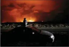  ?? JAE C. HONG — THE ASSOCIATED PRESS ?? Brittany Kimball watches as lava erupts from a fissure near Pahoa, Hawaii, Saturday. Two fissures that opened up in a rural Hawaii community have merged to produce faster and more fluid lava. Scientists say the characteri­stics of lava oozing from...
