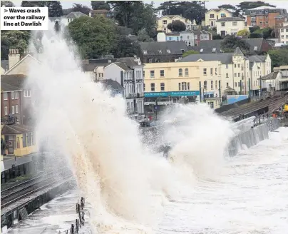  ??  ?? > Waves crash over the railway line at Dawlish