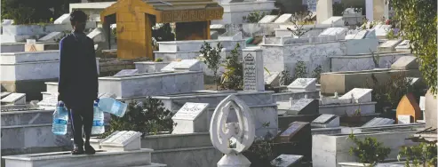  ?? Akhta
r Soomro / Reuters ?? A boy with water-filled containers for sale stands on a grave despite a government-imposed ban on visiting cemeteries during Shab- e-barat, an Islamic festival, amid the COVID-19 crisis in Karachi, Pakistan, on Wednesday.