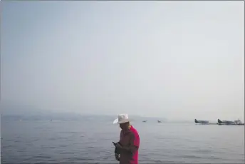  ?? CP PHOTO ?? Smoke from wildfires burning in central British Columbia hangs in the air as a man walks on a dock in Vancouver.