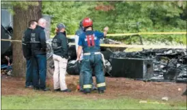  ?? PETER FRANCHELL — OBSERVER-DISPATCH (VIA AP) ?? State police personnel and a firefighte­r examine the charred remains of the mobile home in Rome, N.Y., on Tuesday, July 24, 2018.