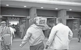  ?? MILWAUKEE JOURNAL PHOTO ?? A baseball fan totes a case of Schlitz into Milwaukee’s County Stadium before a game between the Milwaukee Braves and the Pittsburgh Pirates on June 8, 1962. Milwaukee County had just rescinded a yearlong ban on carry-in beverages, including beer and soda, at the county-owned ballpark. This photo was published in the June 9, 1962, Milwaukee Journal.