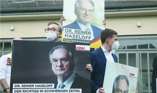  ?? EFE ?? Seguidores del partido conservado­r llevan pancartas del ministro presidente, Reiner Haseloff, que ha arrasado en elecciones regionales