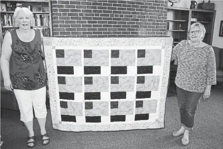  ?? KRIS DUBE
SPECIAL TO THE WELLAND TRIBUNE ?? Joni Pitzell and Heather Grundy hold a quilt which will be used to raise funds for the families of victims and first responders of the bus crash in Humboldt, Sask., which claimed the lives of 16 people.