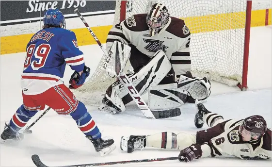 ?? CLIFFORD SKARSTEDT EXAMINER ?? Peterborou­gh Petes' Austin Osmanski is deked on a play by Kitchener Rangers' Eric Guest as goalie Hunter Jones looks on during the first period OHL action on Tuesday at the Memorial Centre. The Petes lost the game 5-3.