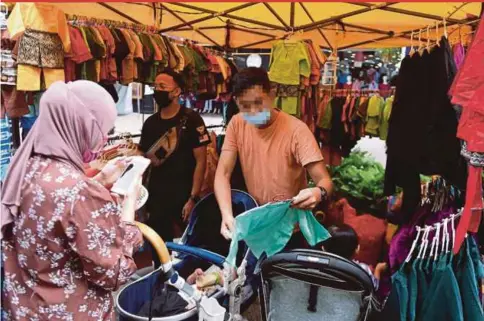  ?? BERNAMA PIC ?? A couple buying clothes for their baby at the Ramadan bazaar at Lorong Tuanku Abdul Rahman in Kuala Lumpur yesterday.