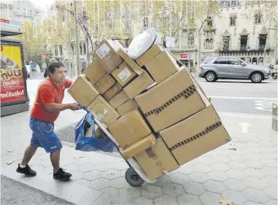  ?? Ricard Cugat ?? Un empleat carrega amb caixes plenes de productes en ple passeig de Gràcia, a Barcelona.