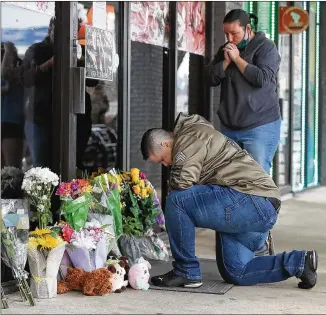  ?? CURTIS COMPTON/ CURTIS. COMPTON@ AJC. COM ?? U. S. Army veteran Latrelle Rolling ( lef t) and Jessica Lang pause Wednesday to pray after dropping off flowers at Youngs Asian Massage, where four people were killed Tuesday. At least eight people were found dead at three spas in metro Atlanta.