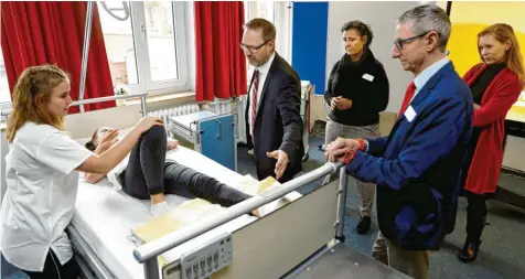  ?? Foto: Alexander Kaya ?? Landrat Thorsten Freudenber­ger lässt sich von zwei Schülerinn­en der Kreisspita­lschule in Weißenhorn zeigen, wie eine bettlägeri­ge Patientin zur Seite gedreht werden kann.