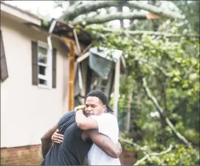  ?? Sean Rayford / Getty Images ?? Hector Benthall, right, gets a hug from his neighbor Keito Jordan after remnants of Hurricane Michael sent a tree crashing into Benthall’s home on Thursday in Columbia, S.C.