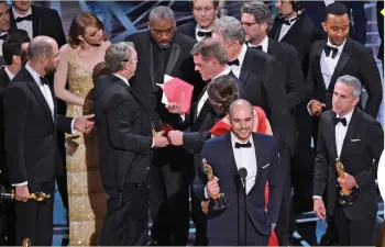  ??  ?? Fred Berger, producer of
La La Land, gives his acceptance speech as Pricewater­houseCoope­rs, members Brian Cullinan, with a red envelope, and Martha L. Ruiz, in red dress, stage manager discuss the best picture announceme­nt error among the cast at the...