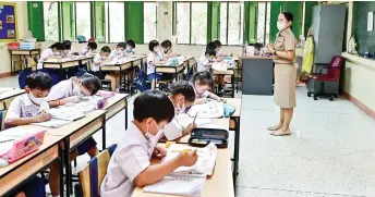  ?? — Pictures by Manan Vatsyayana ?? Pupils are seen wearing face masks inside a classroom with open windows at Suanlumpin­ee School in Bangkok.