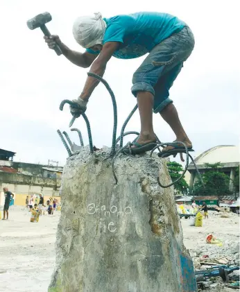  ?? (SUN.STAR FOTO/ARNI ACLAO) ?? SCRAPS. A scavenger removes the steel bars from what’s left of a concrete pillar after the clearing of the CitiCenter Complex in Barangay Kamagayan.