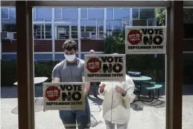  ?? Photograph: Jeff Chiu/AP ?? Volunteers put up signs in support of Gavin Newsom in San Francisco on 14 September.