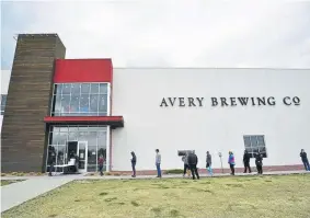  ??  ?? People wait in line for free beer while practicing social distancing at Avery Brewing Co. on Friday in Boulder. Avery Brewing is giving free cases of beer to frontline workers in the fight against the coronaviru­s pandemic that is currently sweeping across the nation.