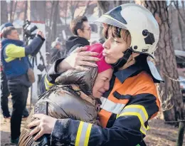  ?? CHRIS MCGRATH/GETTY ?? An emergency services worker comforts a resident after a Russian strike hit an apartment building Tuesday in Kyiv. Russia’s invasion of Ukraine started Feb. 24.