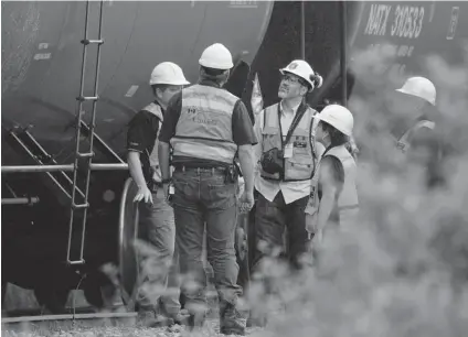  ?? JACQUES BOISSINOT/ THE CANADIAN PRESS ?? Environmen­t Canada emergency inspectors check on nine tanker cars that remain on the tracks in Nantes, Que., Wednesday. There is no evidence linking the accident in Lac- Mégantic to Conservati­ve spending cuts.