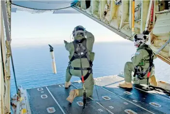  ??  ?? Royal Australian Air Force (RAAF) Loadmaster­s, Sergeant Adam Roberts (L) and Flight Sergeant John Mancey, launch a ‘Self Locating Data Marker Buoy’ from a C-130J Hercules aircraft in the southern Indian Ocean during the search for missing Malaysian...