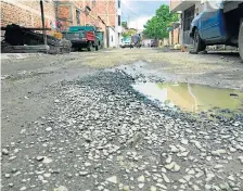  ??  ?? El agua de las lluvias recientes empozada en un enorme bache en el callejón León.