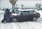  ?? PASCAL GUYOT / AGENCE FRANCE-PRESSE ?? People push a vehicle on a snow covered road in Palavas-les-Flots, France, on Wednesday.
