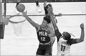  ?? AP-Todd Kirkland ?? Hawks forward De’Andre Hunter recently underwent knee surgery, adding to a number of injuries the team has had to deal with. Here he’s shown going up for a shot as Minnesota Timberwolv­es center Naz Reid (11) and forward Jarred Vanderbilt (8) defend in January.