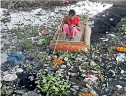  ??  ?? ram Nath, 40, makes a living from recycling trash, rummages for plastic bottles and other reusable trash while rowing a makeshift boat through murky waters of Yamuna. — AP