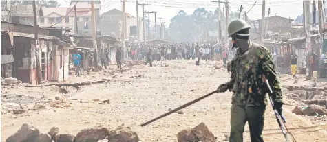  ?? — AFP photo ?? A Kenyan riot police officer clash with supporters of presidenti­al candidate Raila Odinga in the Kawangware slum in Nairobi.