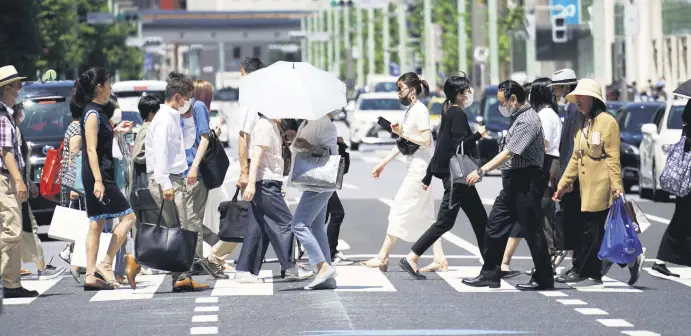  ??  ?? People walk on a pedestrian crossing in Tokyo, Japan, July 2, 2020.