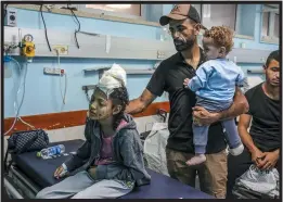  ?? ?? Photojourn­alist Muhammad al-alul holds his surviving son, Adam, and comforts a niece, in Gaza in November. Al-ahul lost three of his other children in a strike near his home in Central Gaza. The familiy is now in Turkey, where al-alul’s wounded wife is being treated.