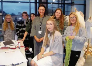  ??  ?? ●● Lottie Coleman (seated) with some of the fashion students and course leader Angela Devoti (centre) at Macclesfie­ld College.