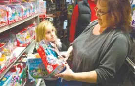  ?? FILE PHOTO BY BEBETO MATTHEWS/THE ASSOCIATED PRESS ?? Cinnamon Boffa, right, from Bensalem, Pa., checks out a “Chubby Puppies” toy for her daughter Serenity, left, at a Toys R Us, in New York. With some holiday toys already in stores, shoppers may want to start planning their strategy.