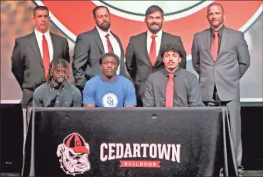  ?? Gail Conner ?? Cedartown seniors Jaquan Darden (seated, from left), Deshawn Ware and Mario Maldonado pose with their football coaches during a signing ceremony at Cedartown High School on April 27. The three committed to playing at the next level and continue their education.