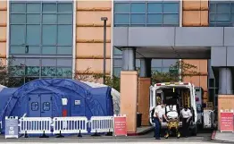  ?? Ashley Landis / Associated Press ?? Medical workers remove a stretcher Dec. 17 from an ambulance near medical tents outside the emergency room at UCI Medical Center in Irvine, Calif.