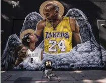  ?? JAE C. HONG ?? FILE - In this Jan. 26, 2021, file photo, Adam Dergazaria­n, bottom center, pays his respects for Kobe Bryant and his daughter, Gianna, in front of a mural painted by artist Louie Sloe Palsino in Los Angeles. Federal safety officials are expected to vote Tuesday, Feb. 9, 2021, on what likely caused the helicopter carrying Kobe Bryant, his 13-year-old daughter and seven others to crash into a Southern California hillside last year, killing all aboard.