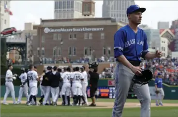  ?? CARLOS OSORIO, THE ASSOCIATED PRESS ?? Toronto Blue Jays relief pitcher Lucas Harrell, foreground, walks off the field as the Tigers celebrate their win in the 11th inning Sunday.