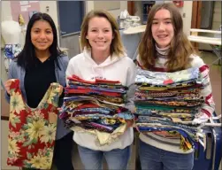  ?? ANDREA PEACOCK/The Okanagan Weekend ?? Harnoor Badyal, left, Courtney Wright and Elise Arbo holding reusable bags sewed by the Rutland Senior Secondary textiles class, which will be handed out to homeless people downtown on Tuesday filled with food and toiletries.