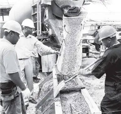  ?? FILE ?? Constructi­on workers watch pre-mix concrete being poured for the retrofitte­d containers being used to house firefighte­rs at the Freeport Fire Station in Montego Bay.