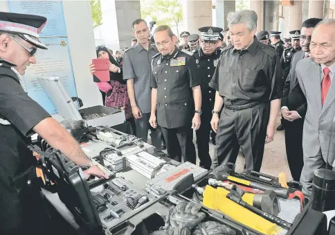  ??  ?? Ahmad Zahid (second right) looking at operation equipment on display at an exhibition booth during the Immigratio­n Day celebratio­ns. Also seen is Immigratio­n chief Datuk Seri Mustafar Ali (third right). — Bernama photo