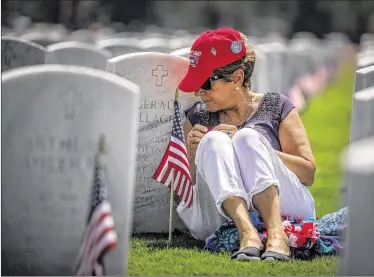  ??  ?? Lorraine Gallagher talks to her husband, Army veteran Gerald Gallagher, who died in 2010, following the Rememberin­g the Fallen Memorial Day ceremony at the South Florida National Cemetery in Lake Worth on Monday. For more photos from the Memorial Day...