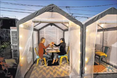  ?? K.M. Cannon Las Vegas Review-journal @Kmcannonph­oto ?? Kerry Callahan, left, and Aubree Toledo dine Monday in an outdoor individual tent at Esther’s Kitchen.